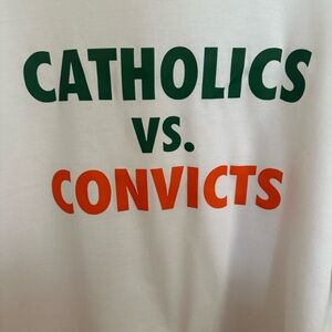 Graphic Tee - 'CATHOLICS VS. CONVICTS' White Tee with Green & Orange Print